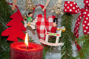Hölzerner Baumschmuck neben einer echten brennenden Kerze. Hier ist die Brandgefahr groß.