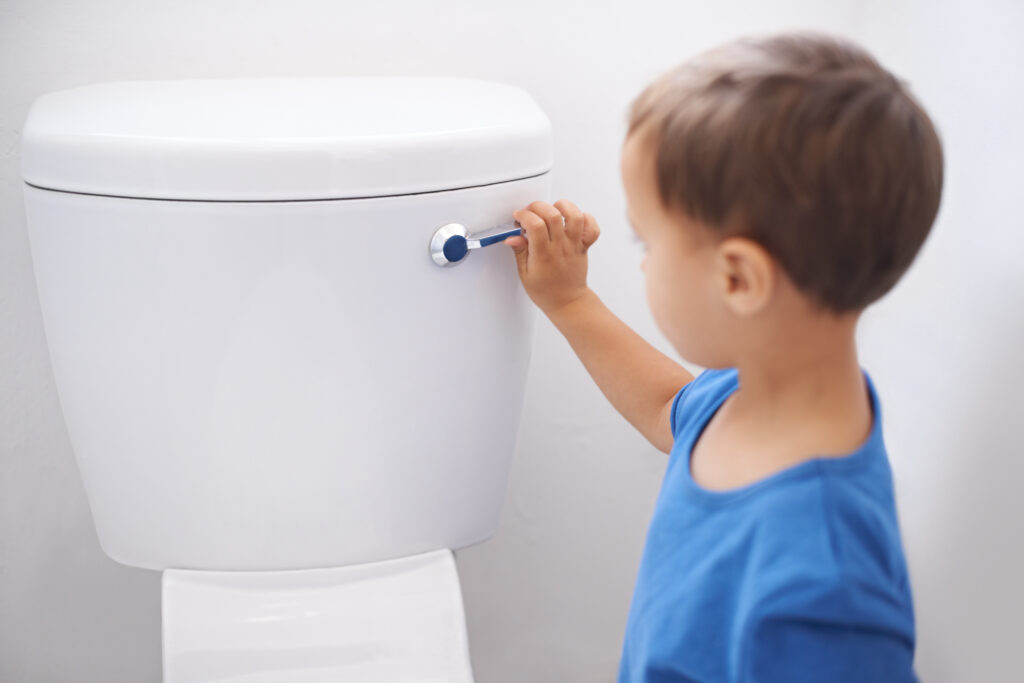Kleiner Junge spült die Toilette