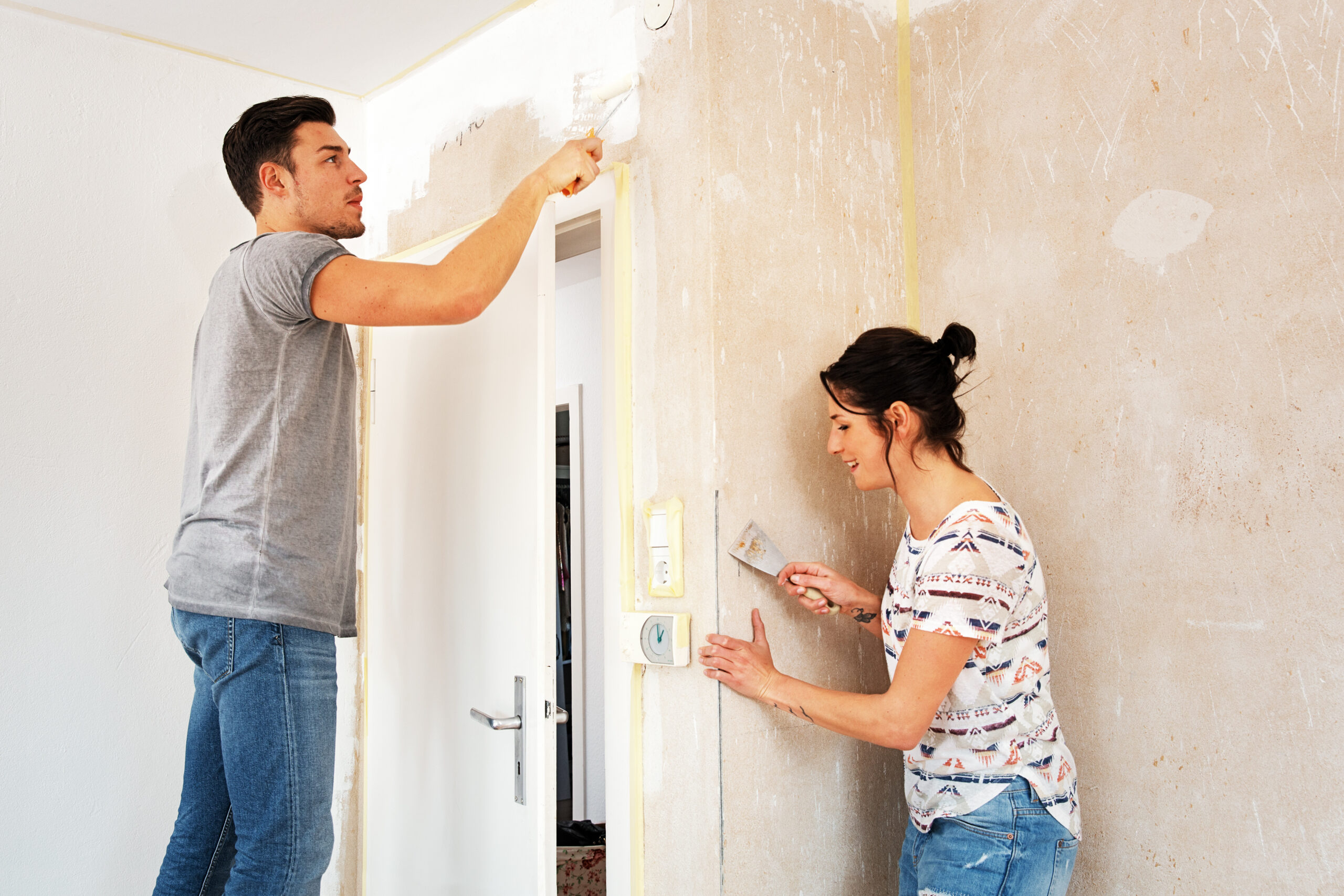 Perfekte Farbflächen: Tipps für ein gelungenes Streichergebnis: Ein Pärchen streicht eine Wand.