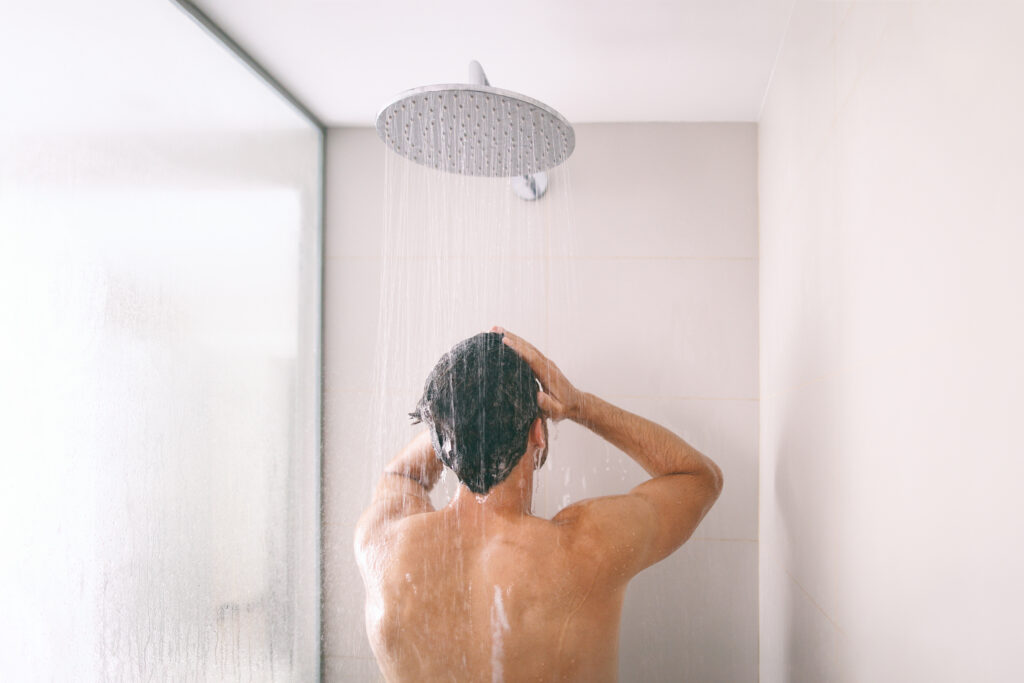 Energiesparen: Ein Mann steht in einer Hell gestalteten Dusche und Duscht.