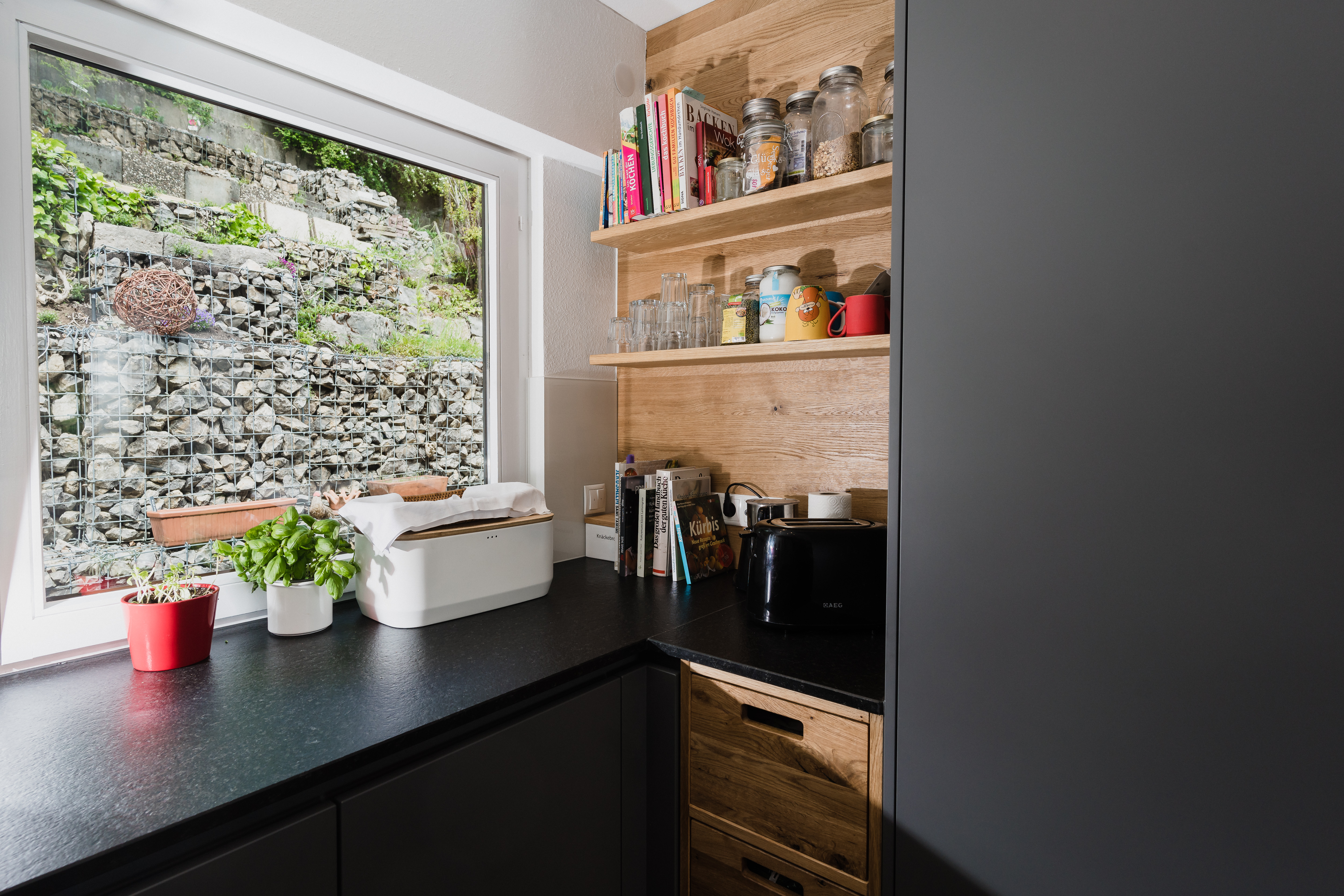 Moderne Küche mit Holzregalen, großem Fenster und Blick auf Natursteinmauer