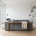 Modernes Wohnzimmer mit grauem Sofa als freistehende Insel mit Walnuss-Konsole dahinter