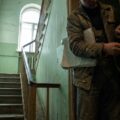 Person misst mit einem Zollstock die lichte Breite einer Wohnungstür im Treppenhaus, um Möbel auszumessen